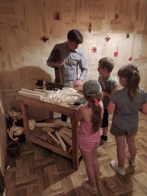 Mężczyzna uczy dzieci korzystać z narzędzi stolarskich