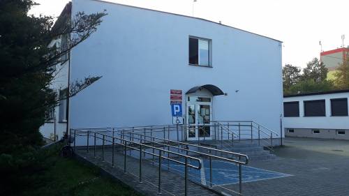 Front budynku Powiatowego Centrum Pomocy Rodzinie w Zawierciu z miejscem parkingowym dla osoby niepełnosprawnej oraz podjazdem dla osób niepełnosprawnych