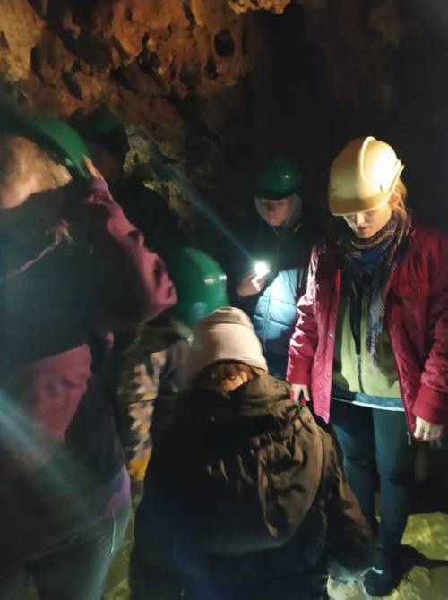 Grupa osób w kaskach na głowach znajduje się w jaskini