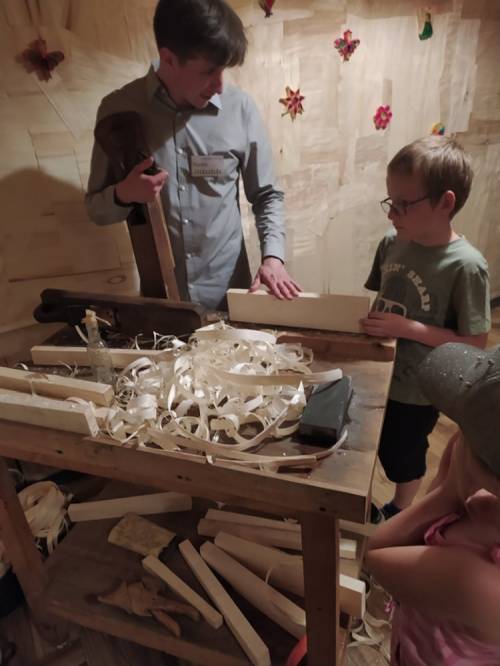 Mężczyzna uczy dzieci korzystać z narzędzi stolarskich