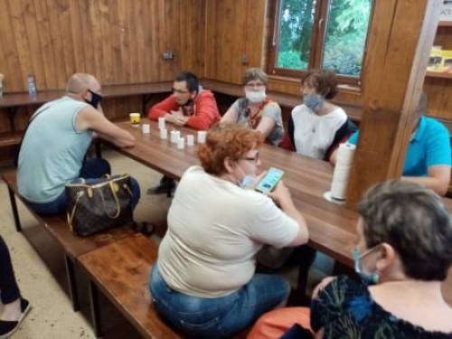 Grupa mężczyzn i kobiet siedząc przy stole ogląda produkty pszczelarskie