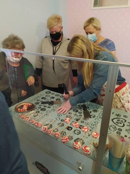 Grupa kobiet foruje szpachelkami słodycze na szablonie z wzorami