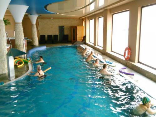 Grupa kobiet i mężczyzn wykonuje ćwiczenia w basenie
