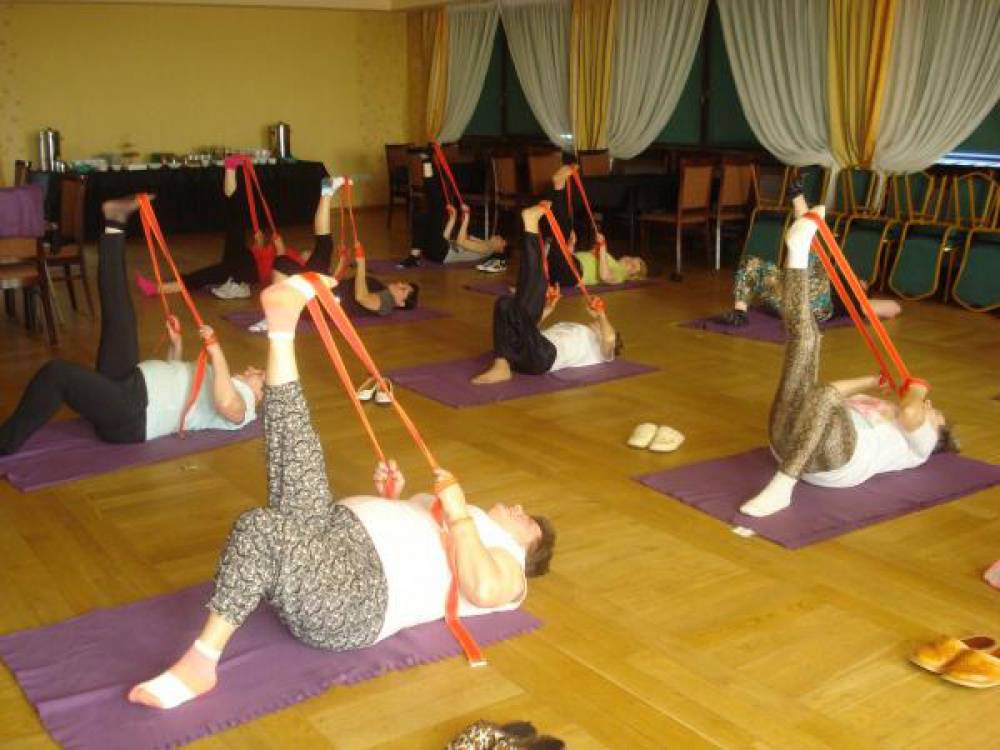 Grupa kobiet leżąc na matach na podłodze wykonuje ćwiczenia z taśmami