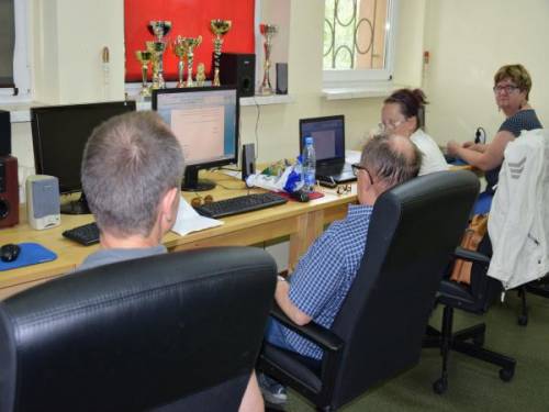 Kobiety i mężczyźni siedzą przy stanowiskach komputerowych