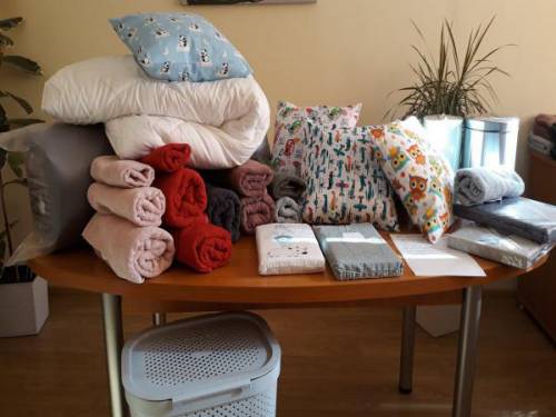 Na stole leżące ręczniki, poduszki, pościele, kosze, materac