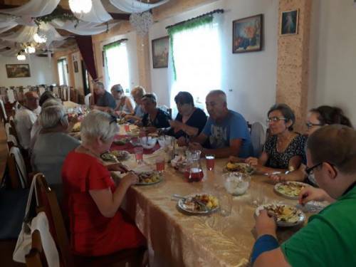 Grupa kobiet i mężczyzn je obiad przy stole