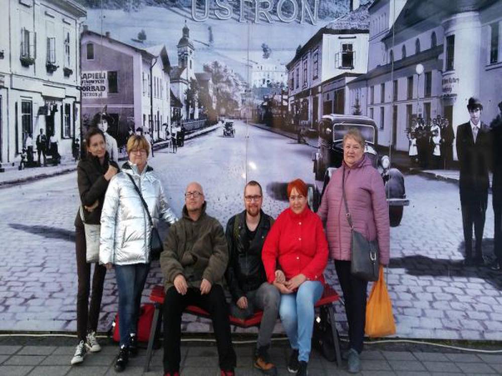 Grupa kobiet i mężczyzn na tle fototapety ukazującej miasto Ustroń