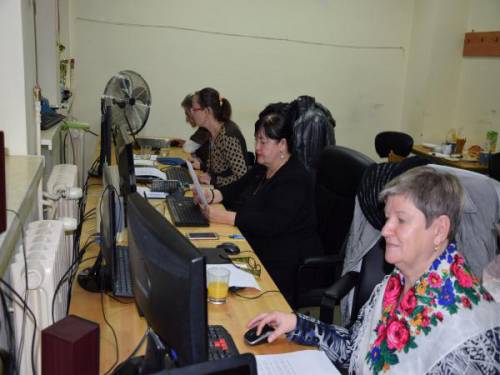 Grupa kobiet siedzi przy stanowiskach komputerowych