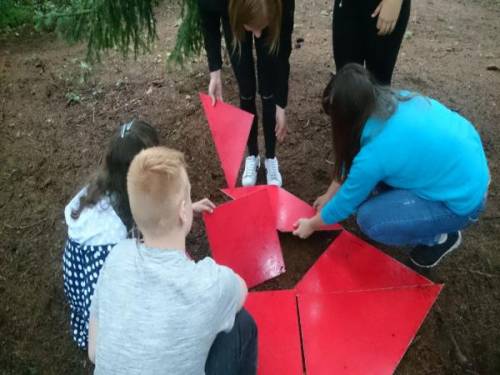 Chłopcy i dziewczynki układają figurę z geometrycznych elementów w kolorze czerwonym